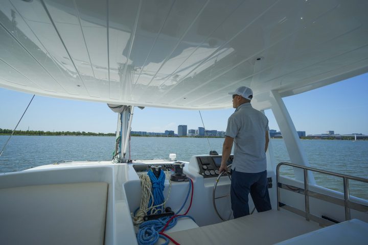 Person standing at the helm of a catamaran